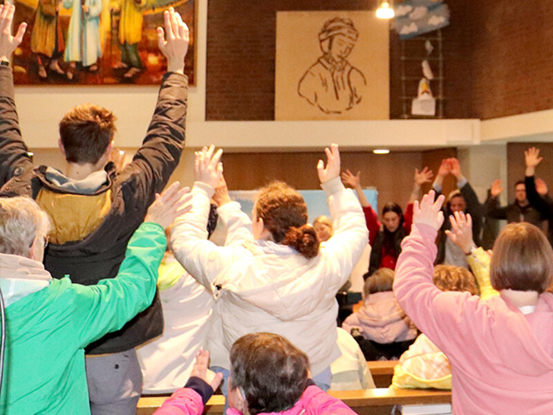 Menschen im Gottesdienst halten die Hände in den Himmel