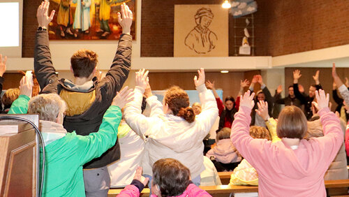 Menschen im Gottesdienst halten die Hände in den Himmel