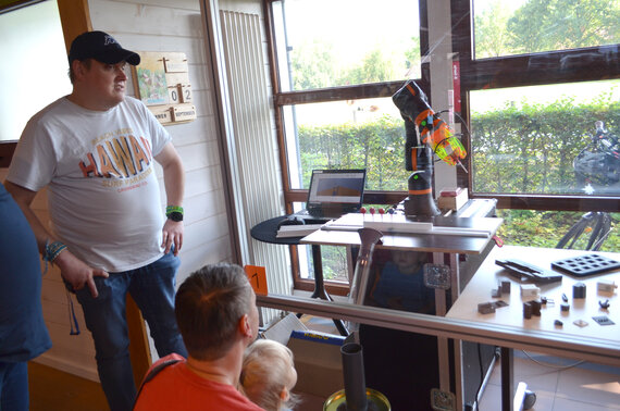 Menschen beobachten einen Roboterarm bei der Arbeit