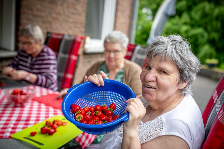 Frau zeigt Schüssel mit Erdbeeren