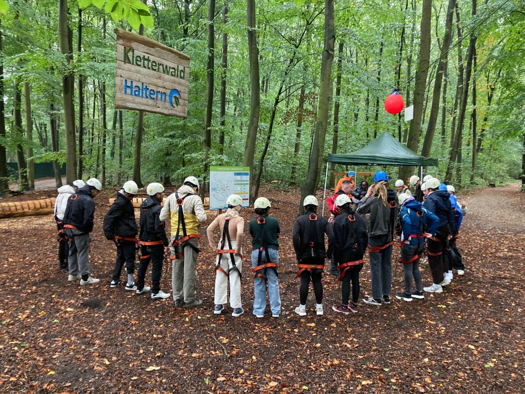 Viele Menschen stehen in einem Halbkreis im Kletterwald